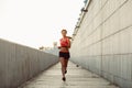 Woman runnning along concrete wall