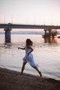 A woman runs along the river bank. Lifestyle portrait of a young woman in a white dress running fast barefoot on a sandy Royalty Free Stock Photo