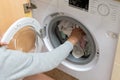 Woman's arm filling the washing machine drum. Concept of energy consumption, high price of electricity, household chores, Royalty Free Stock Photo