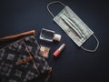 Woman`s bag with lipstick, eye shadow, hand sanitizer gel and face mask.