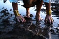 A woman's bare feet and hands with luxury bracelets and rings in a dirty puddle of black mud Royalty Free Stock Photo