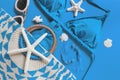 Woman`s beach accessories: bikini, bag, sunglasses, earrings, starfish and shells on bright blue background. Summer creative Royalty Free Stock Photo