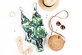 Woman`s beach accessories: swimsuit with tropical print, rattan bag, straw hat on white background. Summer background. Royalty Free Stock Photo