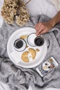 Woman`s bed top view on a lazy sunday morning in cold weather . Lifestyle with mobile phone, book, cakes Royalty Free Stock Photo