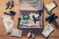 Woman`s clothes, laptop, camer and flag of Saudi Arabia lying on the parquet floor near and in the open suitcase. Travel