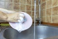 Woman`s cropped hands washes and cleans a sink with a sponge and brush. Royalty Free Stock Photo