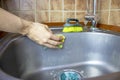 Woman`s cropped hands washes and cleans a sink with a sponge and brush. Royalty Free Stock Photo