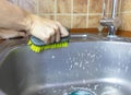 Woman`s cropped hands washes and cleans a sink with a sponge and brush. Royalty Free Stock Photo