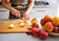 Woman's elegant hands cutting apples on board