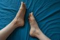 Woman`s feet on blue sheets, self care.