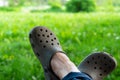 Woman& x27;s feet in garden shoes on green lawn. Relaxing in nature alone concept
