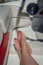 Woman`s feet and legs stretched out in back seat of boat