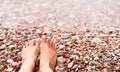 Woman`s feet on a pebble beach on the sea. Vacation and travel concept. Rest, relaxation, sunbathing. Close-up. Copy space. Royalty Free Stock Photo
