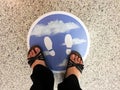 Woman`s feet on the sign on the floor of a supermarket to follow social distancing.