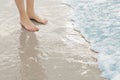 Woman`s feet standing in surf at the beach