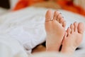 Woman`s feet under the white blanket.rest time, holiday, weekend, woman spending time on the bed, laziness Royalty Free Stock Photo