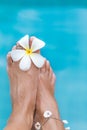 Woman`s female legs in blue swimming pool water with flower Royalty Free Stock Photo