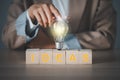 Woman`s finger touching light bulb on a wooden block with Ideas word Royalty Free Stock Photo