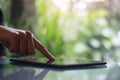 A woman`s finger touching and pointing at tablet pc on glass table with blur background in cafe Royalty Free Stock Photo