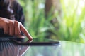 A woman`s finger touching and pointing at tablet pc on glass table with blur background in cafe Royalty Free Stock Photo