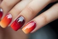 Woman\'s fingernails with red and orange nail polish