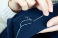 Woman`s fingers with thread and needle stitching fabric. Hands sewing, repairing clothes Tailoring and homecraft concept