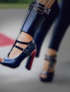 Woman`s foot in a high-heeled black leather shoe with fine straps and a wide, unusual cuff over the ankle, made with generative A