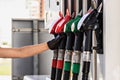 A woman`s gloved hand reaches for a gasoline pump pistol at a gas station. Refueling the car Royalty Free Stock Photo