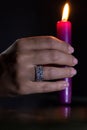 A woman`s hand with a beautiful silver ring holds a lit purple candle Royalty Free Stock Photo