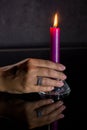 A woman`s hand with a beautiful silver ring holds a lit purple candle Royalty Free Stock Photo