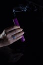 A woman`s hand with a beautiful silver ring holds a smoking purple candle Royalty Free Stock Photo