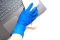 A woman`s hand in blue rubber glove with white cloth wipes the keyboard of a laptop. concept of home cleaning and order Royalty Free Stock Photo