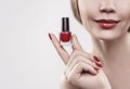 Woman`s hand with a bottle of red nail polish. Isolated on white background. Royalty Free Stock Photo