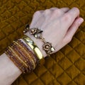 Woman's hand with bracelets and rings on the background of a golden fabric Royalty Free Stock Photo