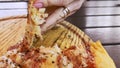 Woman\'s hand breaks slice of hot, fragrant pizza lying on wooden tray. Unhurried camera movement