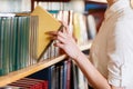 A woman`s hand chooses a book in the library. Royalty Free Stock Photo