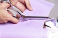 Woman`s hand cutting purple fabric