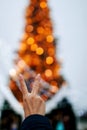 Woman`s Hand On Defocused Bright Ligths Of Decorated Christmas Tree