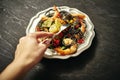 A woman`s hand and delicious black spaghetti with grilled shrimps and vegetables, on silver plate Royalty Free Stock Photo