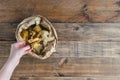 Woman`s hand depositing a banana peel in a paper bag to make compost