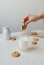 A woman's hand dips a cookie into a glass of milk. Glass glass with milk and cookies