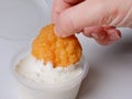 A woman`s hand dips nuggets in Tartar sauce on a gray background, close-up