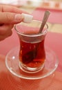 Woman`s Hand Dropping a Sugar Cube into the Glass of Turkish Tea Royalty Free Stock Photo