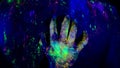 Woman's hand erotically slips on the man's on the back under ultraviolet light.