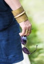 Woman's hand with eyeglasses and brass jewelry