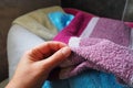 A woman's hand is feeling a cotton colored towel from a basket with dirty laundry.