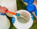 A woman's hand fills a plastic barrel with water from a hose. The concept of the drinking water crisis in the world