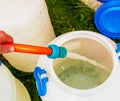 A woman's hand fills a plastic barrel with water from a hose. The concept of the drinking water crisis in the world