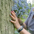 A woman's hand with flowers near a tree trunk