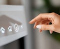 A woman's hand gently touches a smart home control panel, activating a power button Royalty Free Stock Photo